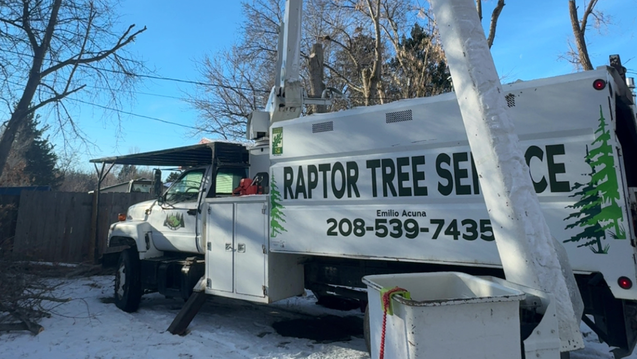 Raptor Tree Service work truck with crane in a snowy yard in Jerome, Idaho